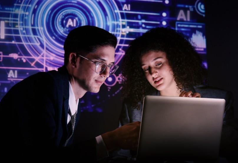 Two people looking at a laptop screen with AI-themed graphics in the background