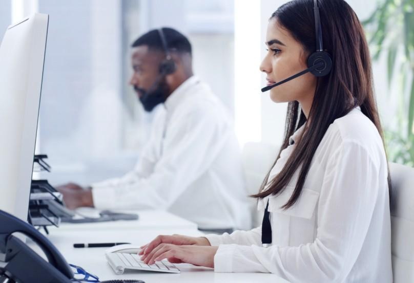 Two people working at computers with headsets