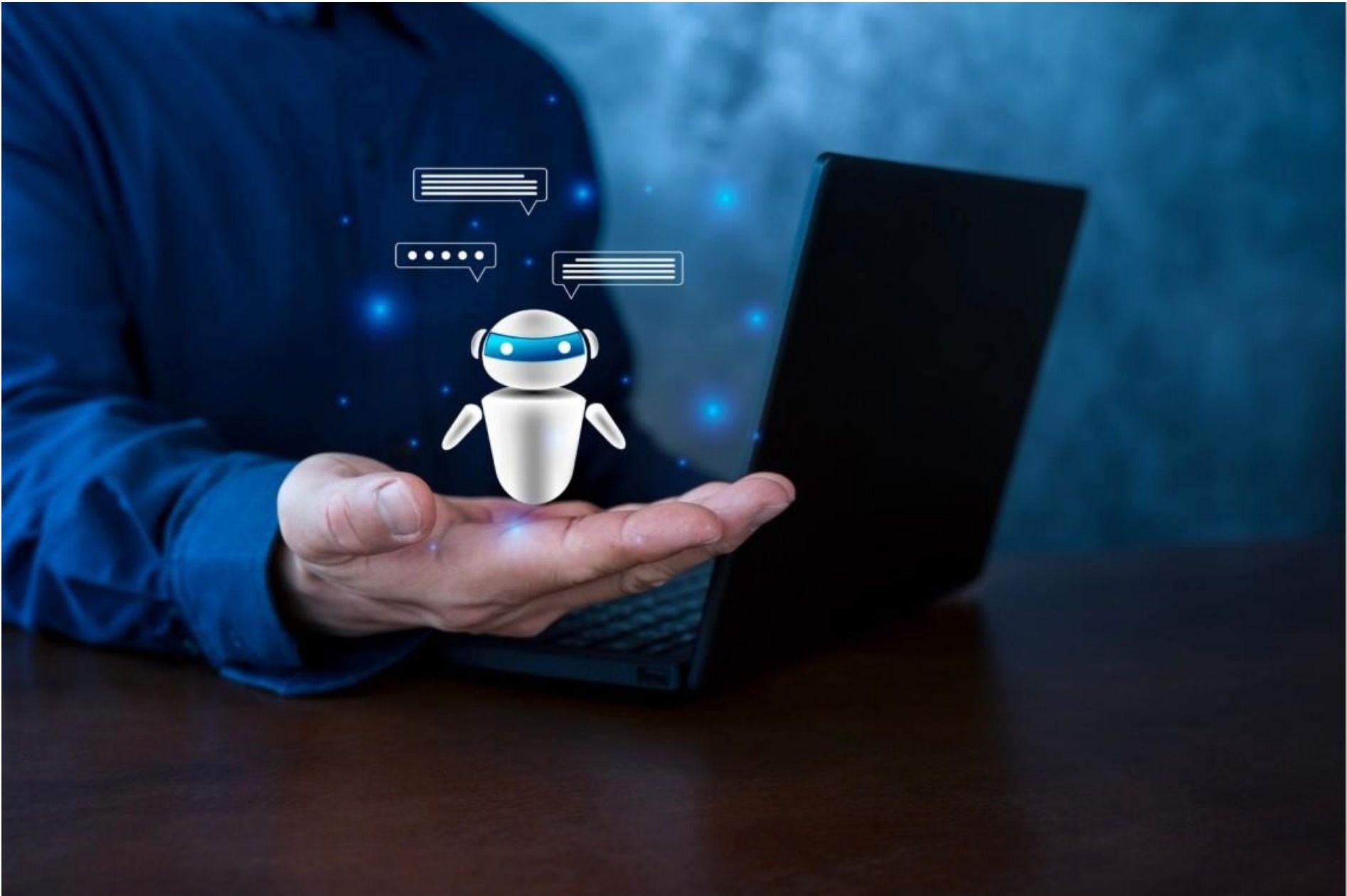 A person holding a small robot in their hand with a laptop in the background