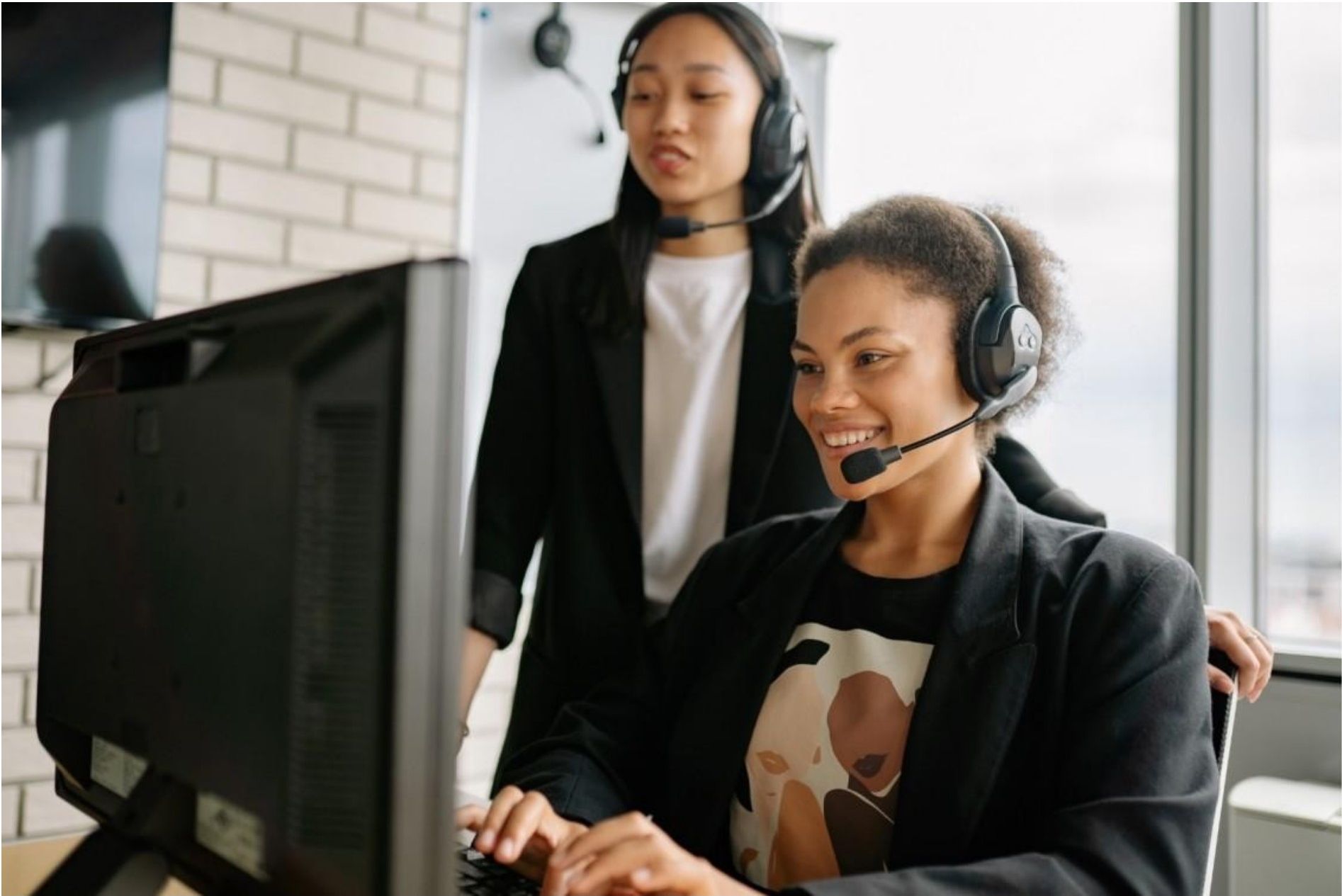 Two women wearing headsets working at a computer