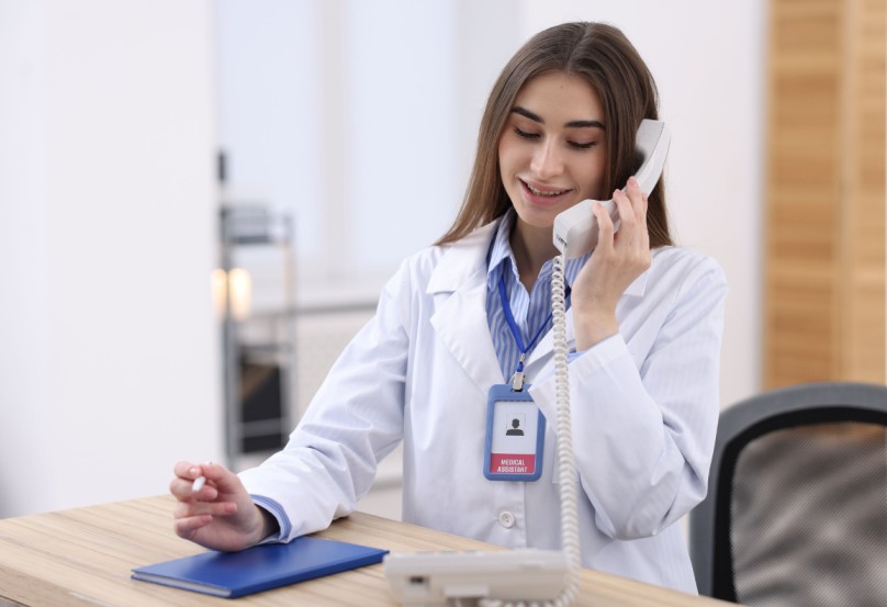 A medical professional speaking on the phone at a desk